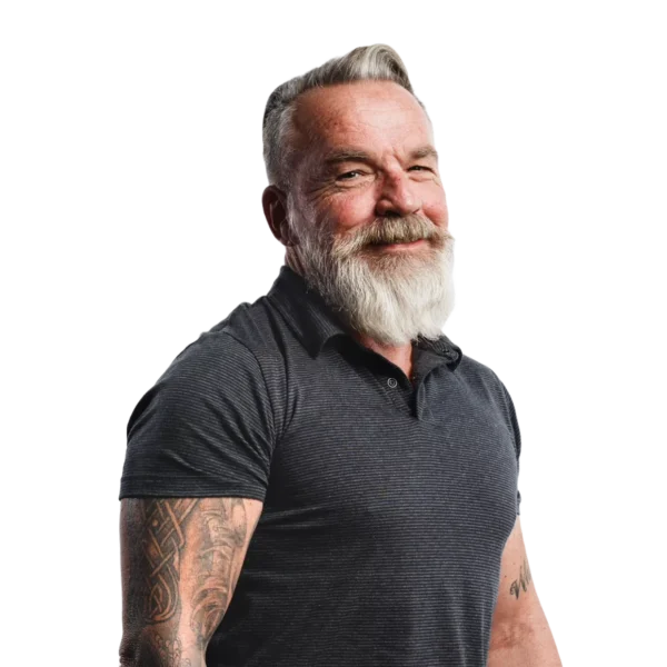 Muscular mature man with white beard and athletic fitting polo shirt, arms with tattoos, smiling at the camera, friendly.